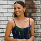 Leslie Grace attends the opening night premiere of In The Heights wearing a strappy dress and hair parted down the middle.